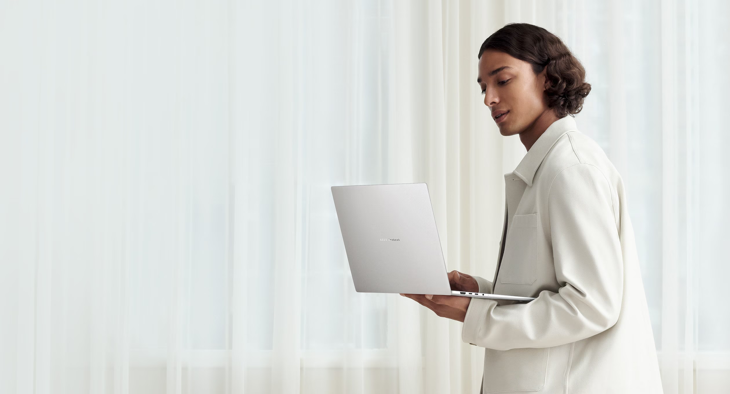 A person working on a silver laptop in soft, sunlit light